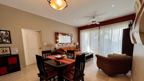 A dining area with a table and chairs, a sofa, and a window with curtains. - Beguiling pool-ocean view unit (La Paz)
