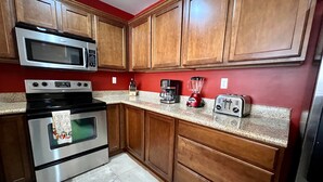 A kitchen with wooden cabinets, a stainless steel oven, a microwave, a toaster, and a blender. - Beguiling pool-ocean view unit (La Paz)