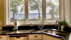 Une cuisine donnant sur un lac, une enseigne indiquant « LAKESIDE RETREAT », et un égouttoir à vaisselle posé sur le comptoir.
