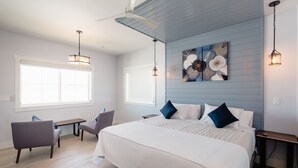 Une chambre à coucher avec un grand lit, deux chaises, un bureau et un ventilateur de plafond.