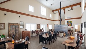 Une salle à manger spacieuse avec de hauts plafonds, des poutres en bois et de grandes fenêtres.