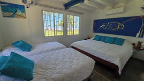 A room with two beds, a large window with a view of palm trees, and a ceiling fan. - Air conditioner in all the bedrooms, swimming pool, experience the pura vida!  (Guanacaste)