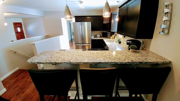 Una cocina moderna con encimeras de granito, electrodomésticos de acero inoxidable e iluminación colgante.
