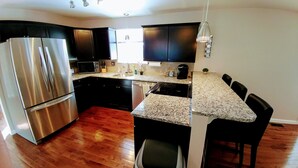 Una cocina moderna con electrodomésticos de acero inoxidable, armarios oscuros y una encimera de granito.