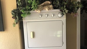 A stacked washer and dryer unit with a small table beside it.