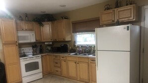 A kitchen with wooden cabinets, a white refrigerator, a microwave, a stove, and a sink.