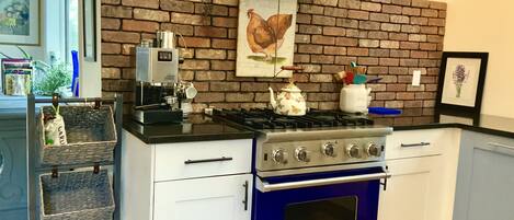 Cuina amb un mur de rajoles, un fogó a gas i un forn blau.