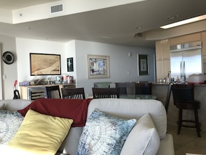 Een moderne woonkamer met een bank, een eethoek en een keuken met roestvrijstalen apparatuur.