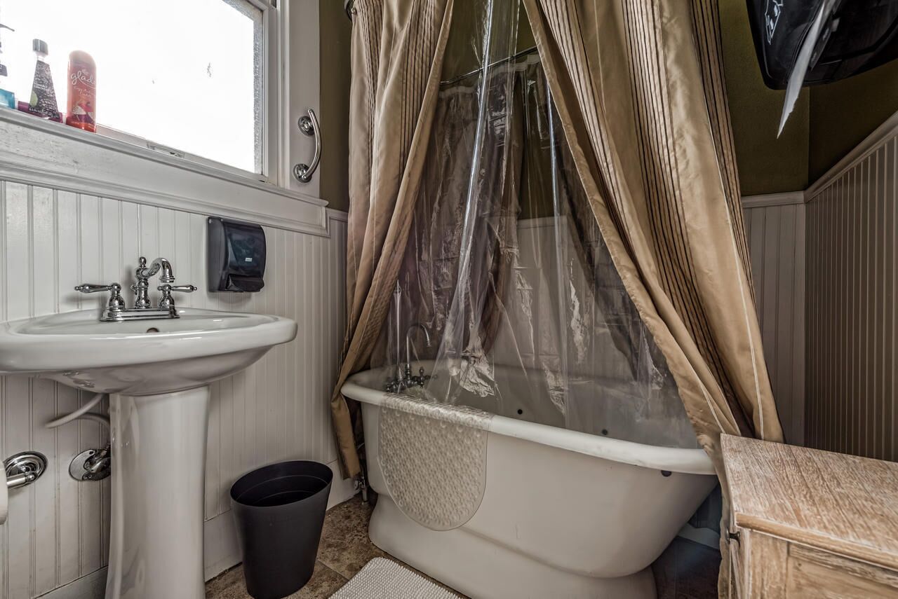 Ein Badezimmer mit einem weißen Waschbecken, einer Badewanne mit Duschvorhang und einem Fenster über dem Waschbecken.