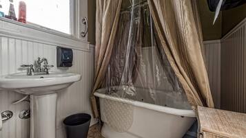 Ein Badezimmer mit einem weißen Waschbecken, einer Badewanne mit Duschvorhang und einem Fenster über dem Waschbecken.