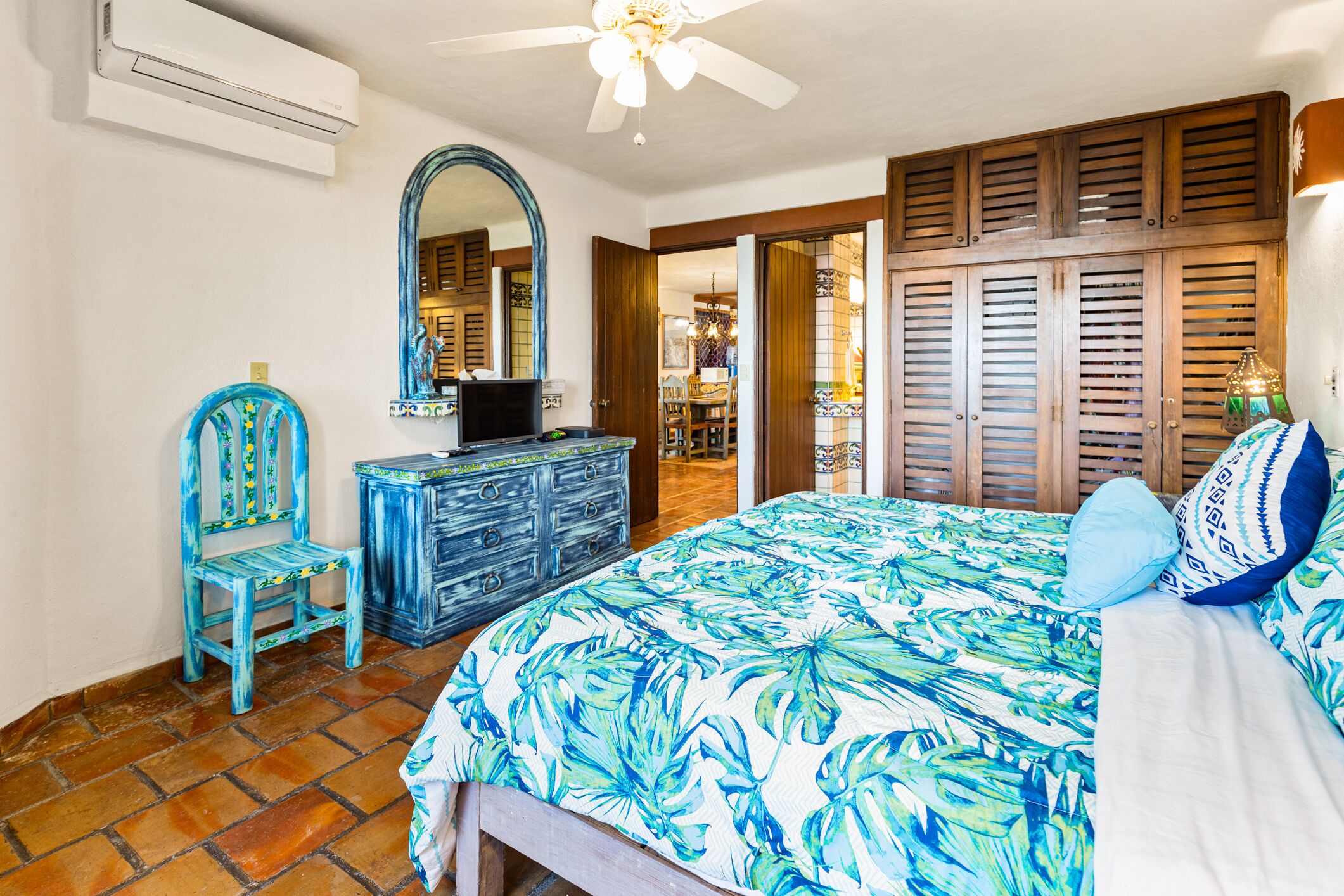 Quarto com cama, penteadeira, cadeira e espelho.