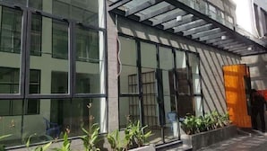A modern building with large glass windows, a covered entrance, and potted plants. - Min Apartment (Ho Chi Minh City)