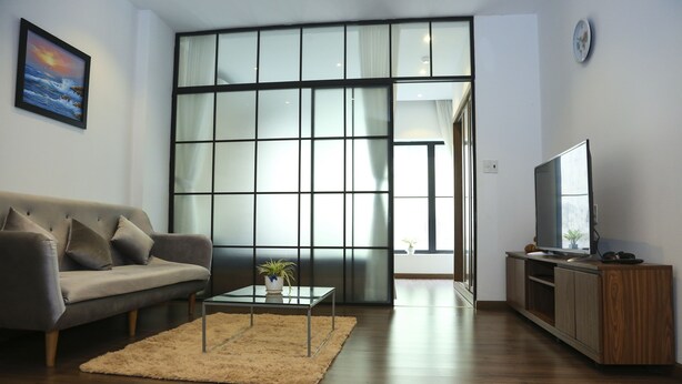 A living room with a sofa, a coffee table, a TV, and a sliding glass door. - Min Apartment (Ho Chi Minh City)