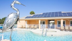 En swimmingpool med ett tak bestående av solpaneler, solstolar och en fågelskulptur.