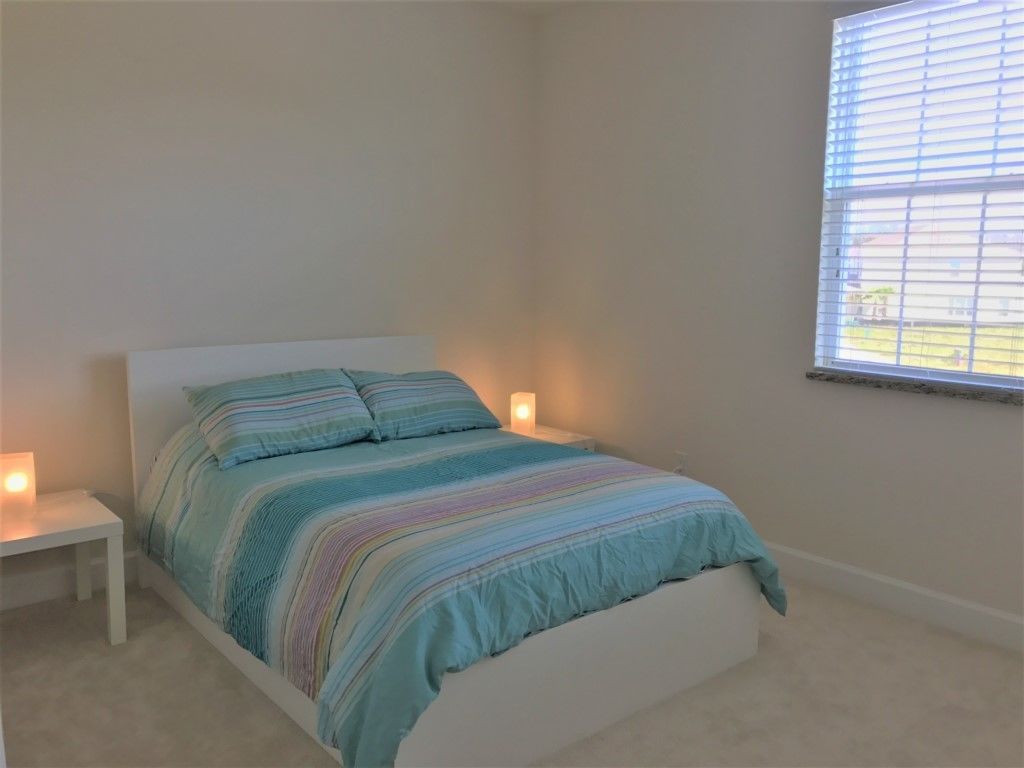 A bedroom with a bed, bedside lamps, and a window.