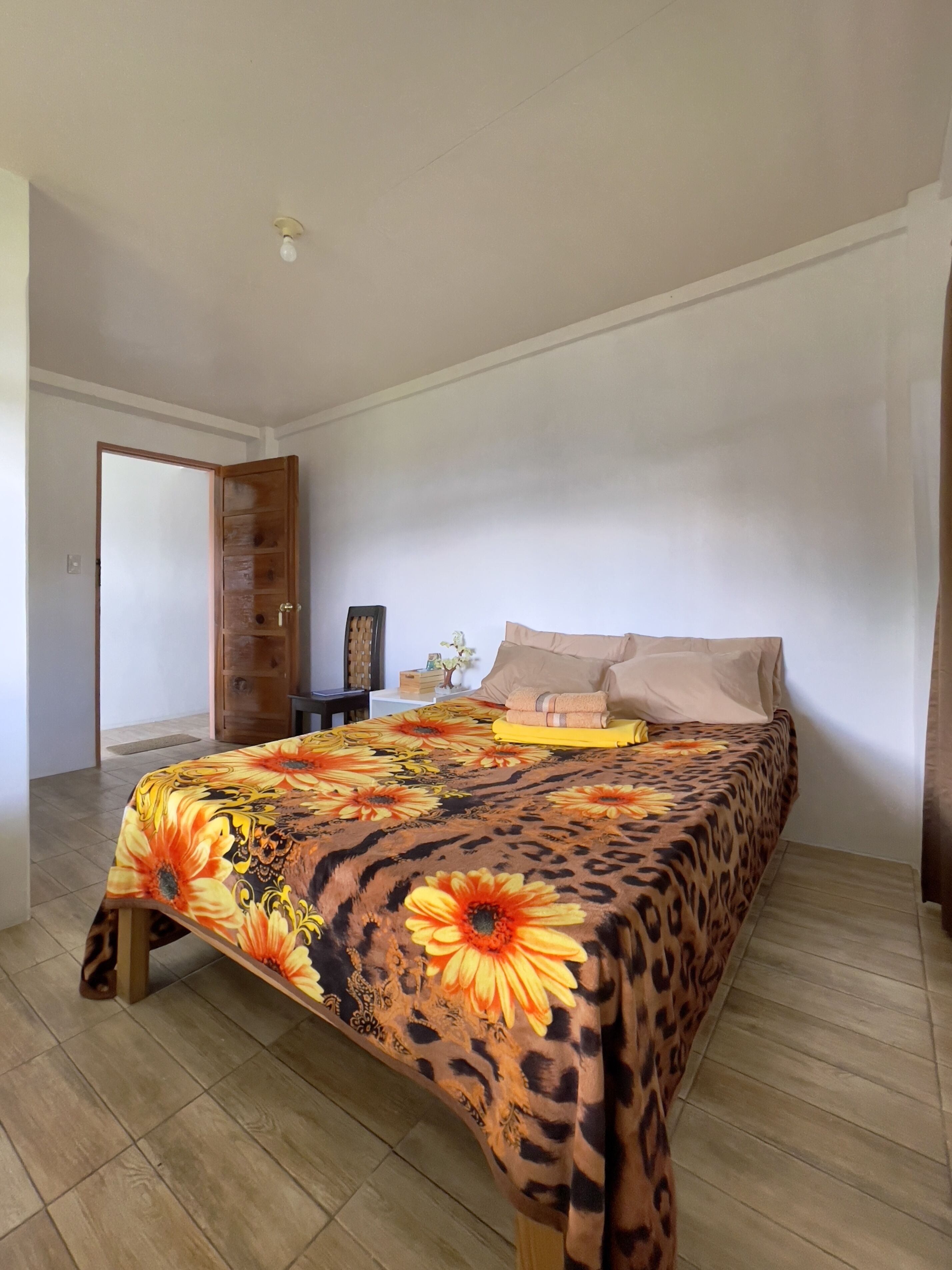 A bedroom with a bed, a nightstand, a lamp, and a door.