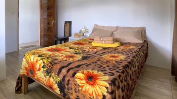 A bedroom with a bed, a nightstand, a lamp, and a door.