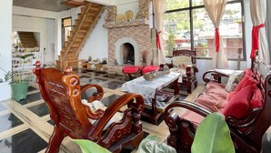 Un vaste salon doté d’un haut plafond, d’une cheminée et d’un escalier menant à un autre niveau.