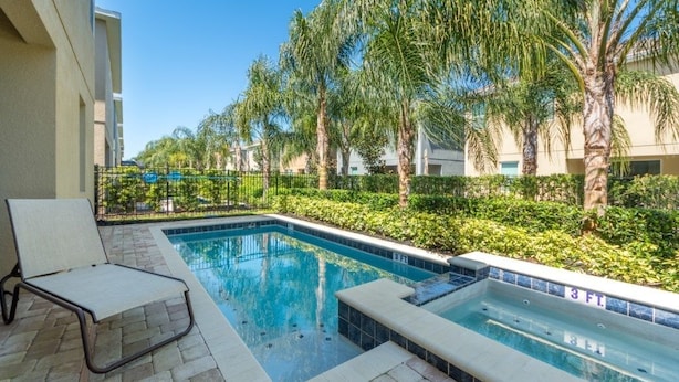 A swimming pool with a lounge chair, surrounded by palm trees and a fence. - Aco255240 - The Encore Club Resort - 8 Bed 7 Baths Villa (Kissimmee)