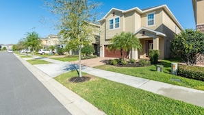A residential street with two-story houses, a sidewalk, and a clear blue sky. - Aco255240 - The Encore Club Resort - 8 Bed 7 Baths Villa (Kissimmee)