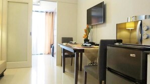 Ein Hotelzimmer mit Essbereich, einem flachbildfernseher an der Wand und einem Kühlschrank.