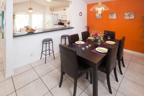 Un comedor con una mesa de madera oscura, seis sillas y una isla central con taburetes.