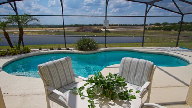 A pool area with two chairs and a table, surrounded by a covered patio. - Ahr105 - Sunset Ridge - 5 Bed 3 Baths Villa (Davenport)