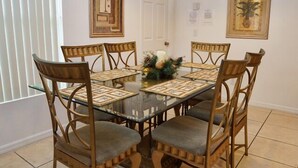A dining area with a glass table surrounded by six wooden chairs with cushioned seats. - Ahr105 - Sunset Ridge - 5 Bed 3 Baths Villa (Davenport)