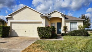 A single-story house with a garage, a front door, and a small front yard with bushes. - Ahr105 - Sunset Ridge - 5 Bed 3 Baths Villa (Davenport)