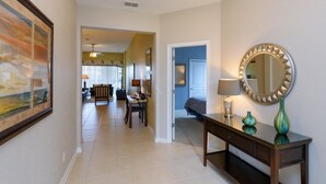 A hallway with a wooden console table, a round mirror, and a framed picture on the wall. - Fv64670 - Windsor Hills Resort - 4 Bed 4 Baths Villa (Kissimmee)