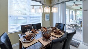 A dining area with a table set for six, surrounded by black leather chairs. - Fv64670 - Windsor Hills Resort - 4 Bed 4 Baths Villa (Kissimmee)