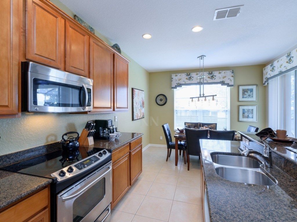 A kitchen with wooden cabinets, a stainless steel microwave, a stove, and a sink.