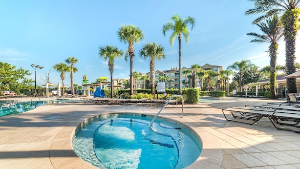 A swimming pool with a curved edge, surrounded by palm trees and lounge chairs. - Fv64670 - Windsor Hills Resort - 4 Bed 4 Baths Villa (Kissimmee)