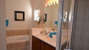 A bathroom with a bathtub, two sinks, a large mirror, and a shower area. - Ip60393 - The Shire at West Haven - 4 Bed 3 Baths Villa (Davenport)