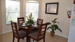 A dining area with a round table, four wooden chairs, a potted plant, and a framed picture on the wall. - Ip60393 - The Shire at West Haven - 4 Bed 3 Baths Villa (Davenport)