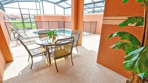 A covered outdoor patio with a pool, seating area, and a large plant. - Fv53300 - Paradise Palms - 4 Bed 3 Baths Townhome (Kissimmee)