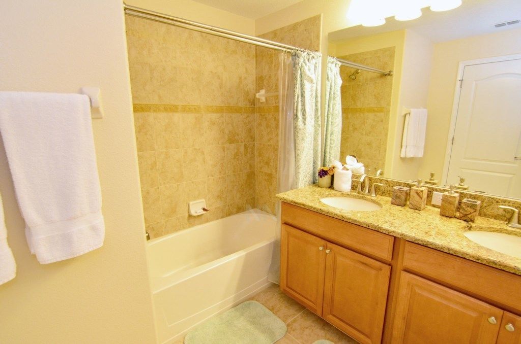 A bathroom with a bathtub, two sinks, wooden cabinets, and a mirror.
