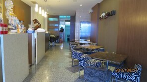 A restaurant with zebra-patterned chairs and tables, a reception area with a counter, and a view of the street. - Tan Hui Hotel (Yuchi)