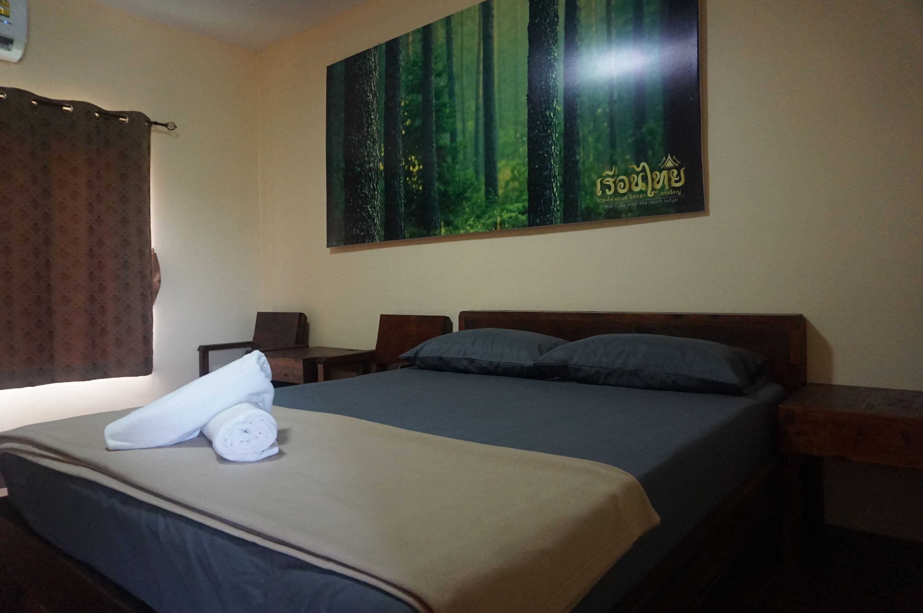 Una habitación de hotel con una cama, una mesita de noche, un cabecero de madera, un cartel en la pared y una ventana con cortinas.