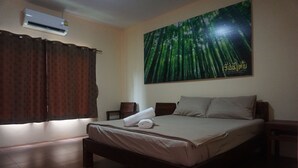 A bedroom with a bed, a nightstand, a wall-mounted air conditioner, and a large poster of a forest. - Thai House Hotel & Resort Hat Yai (Hat Yai)