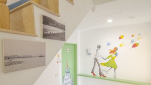 Un pasillo con obras de arte en las paredes, una puerta verde y una estantería con un personaje de caricatura.