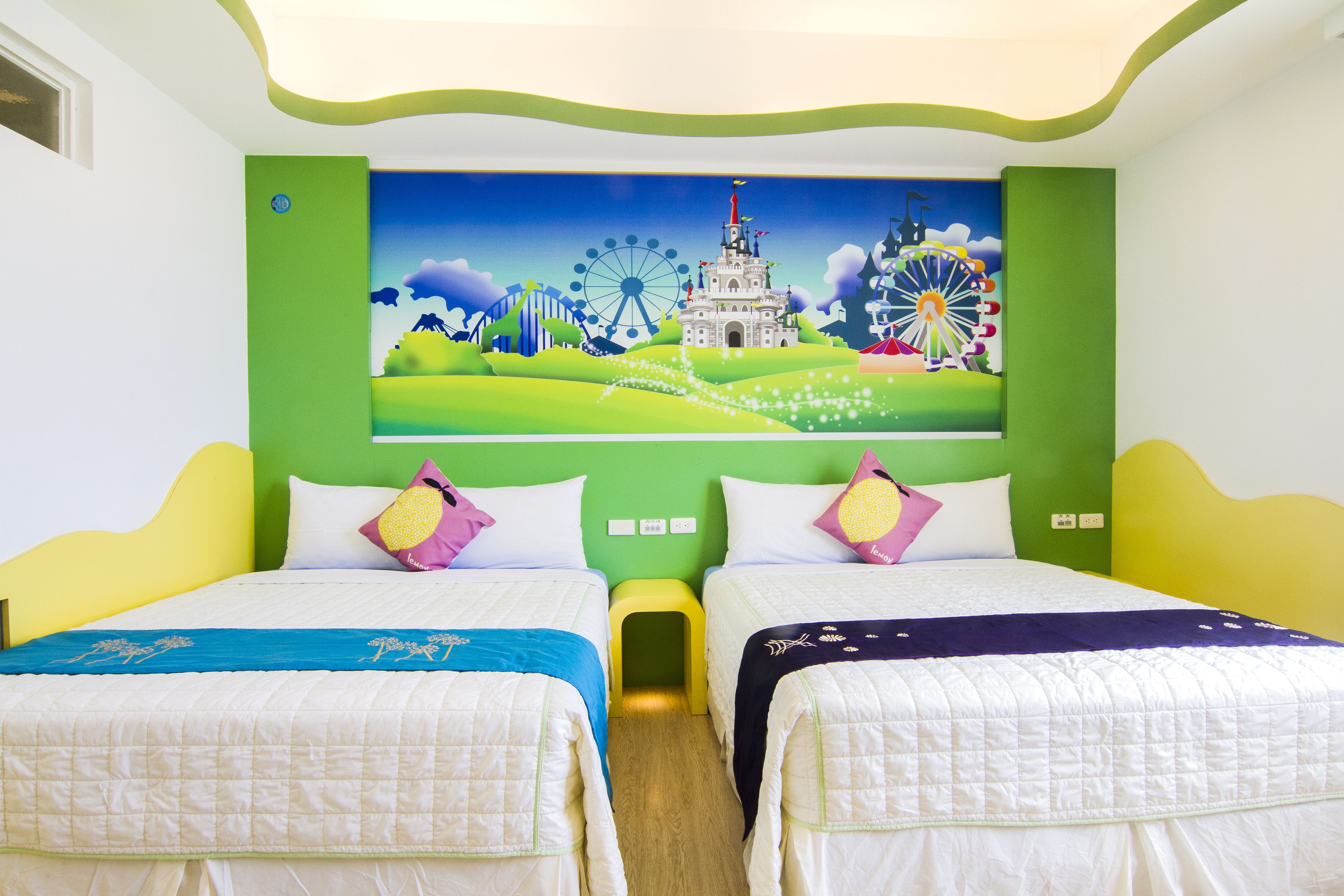 A hotel room with two beds, a mural of a cityscape, and a green accent wall.