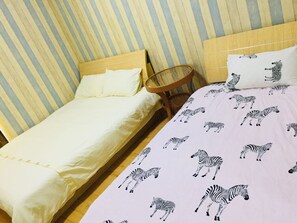 Relax in a cozy space with a striped wallpaper background, a comfortable bed with a zebra print bedspread and matching pillows, and a wicker chair for a quiet retreat.