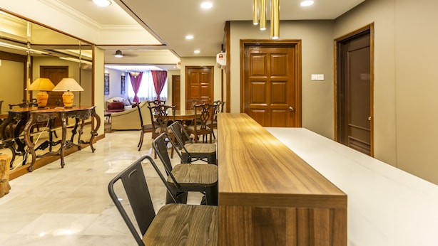 Un espace de restauration d’hôtel avec une longue table en bois, plusieurs chaises et un lustre.