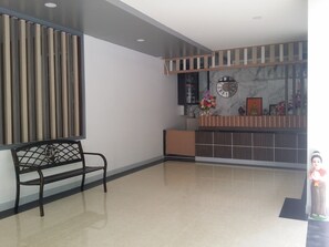 A reception area with a bench, a reception desk, a clock, and a decorative wall.