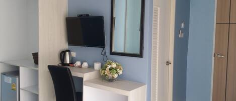 Habitación de hotel con escritorio, silla, televisor y espejo.