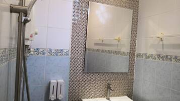 Un baño con ducha, lavabo y espejo.
