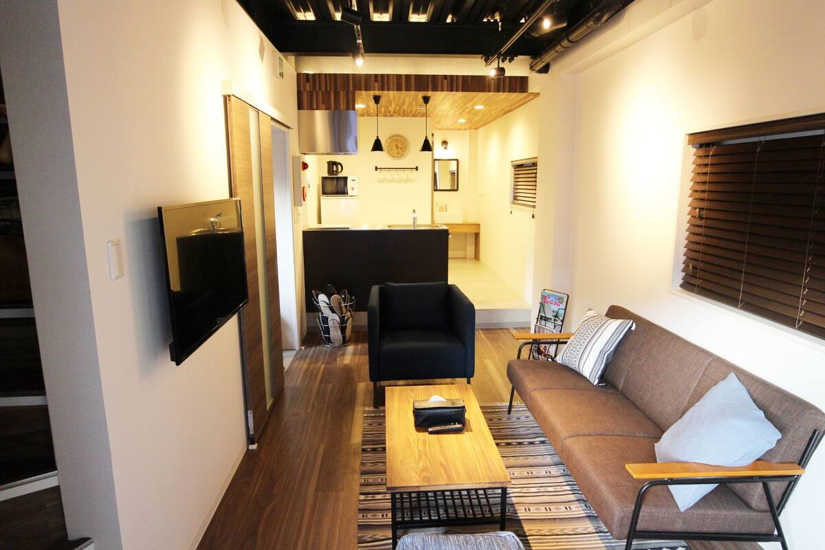 Una sala de estar moderna con un sofá, una mesa de centro y un televisor montado en la pared.