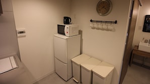A compact kitchen with a refrigerator, microwave, and a clock on the wall. - Neighbors Kaede (Osaka)