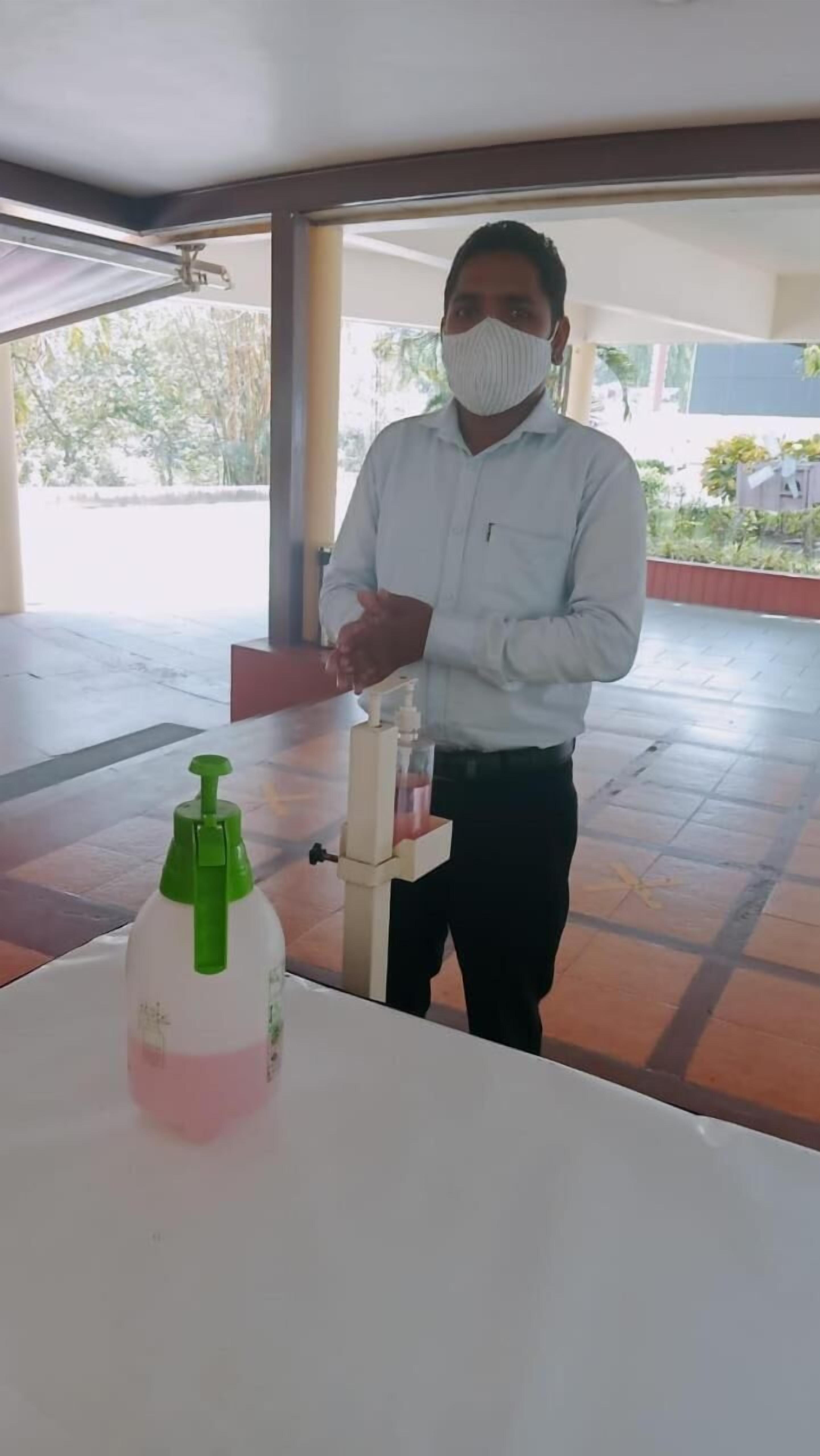 A person standing in a covered outdoor area with a table in front of them.